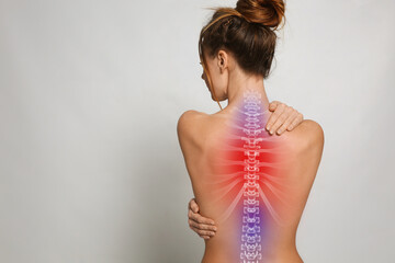 Woman suffering from pain in back on light background, space for text