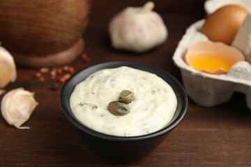 Creamy caper sauce in bowl on wooden table, closeup