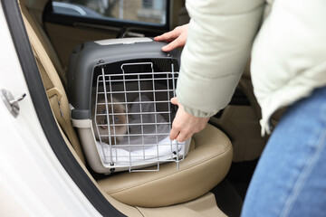 Woman closing pet carrier with cat in car, closeup