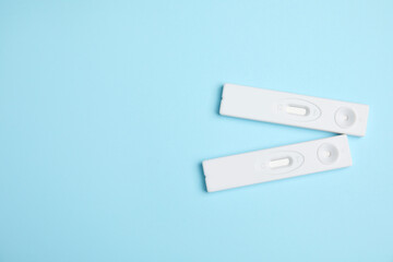 Two disposable express hepatitis tests on light blue background, flat lay. Space for text
