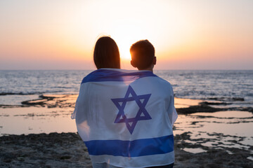 Teenagers, young women and man with the Flag of Israel draped over their shoulders at the sunset...