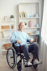 Portrait of content disabled aged man with gray hair sitting in wheelchair in modern room with shelves in background