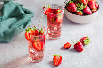 Two glasses with a strawberry cocktail and a bowl of berries on the table. Homemade drinks