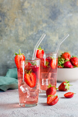 Refreshing cocktail with strawberries in glasses with a straw on the table. Vertical view