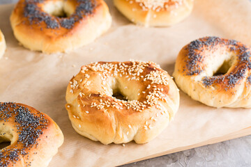 Baked bagels with poppy seeds and sesame seeds on parchment. Homemade pastries. Close-up