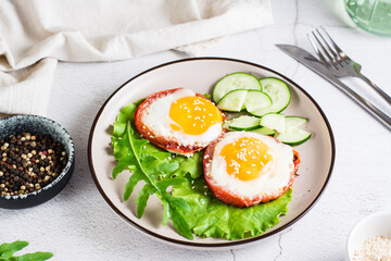 Eggs baked in tomato, arugula leaves and cucumber on a plate on the table. Homemade lunch