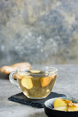 Fresh ginger tea in a cup and chopped ginger in a bowl on the table. Natural Vitamins. Vertical view