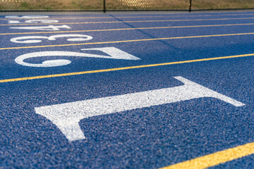 Inspiring close up of a new blue running track with yellow lane lines and other markings.