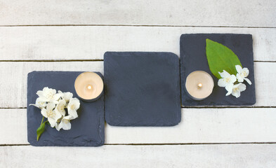 jasmine flowers and candles on wooden table, on stone stands