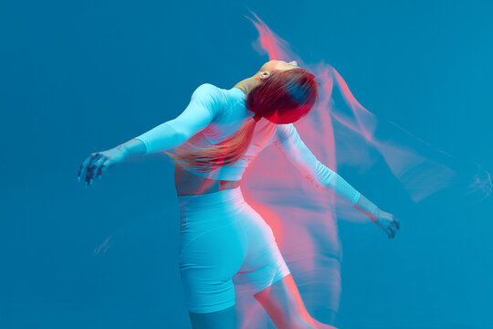 Sporty Beautiful Girl In White Tracksuit Dancing On Blue Background. Isolated Fitness Model In Studio With Motion Blur Effect.