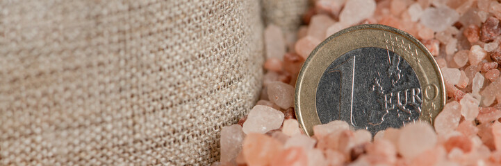 Salt price. Large crystals of pink Himalayan salt, close-up. A coin in a pile of salt as a symbol...