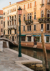 Picturesque venetian street next to a canal and traditional street light in Venice, Italy 