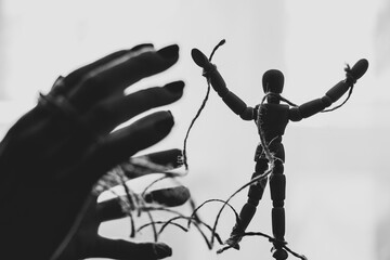 Wooden puppet tied with ropes to the puppeteer, manipulation of people, people are slaves, propaganda - obrazy, fototapety, plakaty