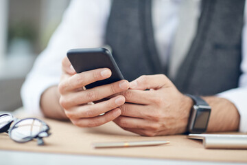 Close-up of unrecognizable businessman sitting at table and using mobile internet on smartphone