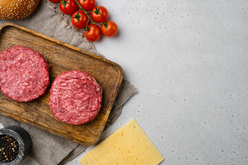 Organic raw ground beef, round patties for making homemade burger on gray stone table background,...