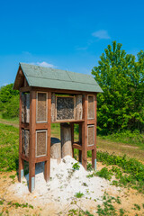 Insect hotel in a green hedge gives protection. Wooden insect house shelter for wild insects in forest reserve