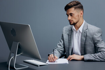 manager in a gray suit sits in front of a computer executive