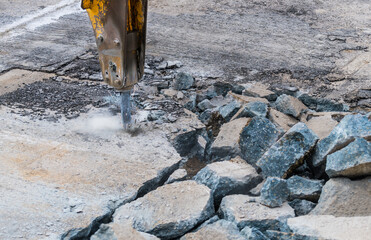 Close-up of demolition hammer with dust and sparks and broken concrete pieces. Detail of hydraulic...