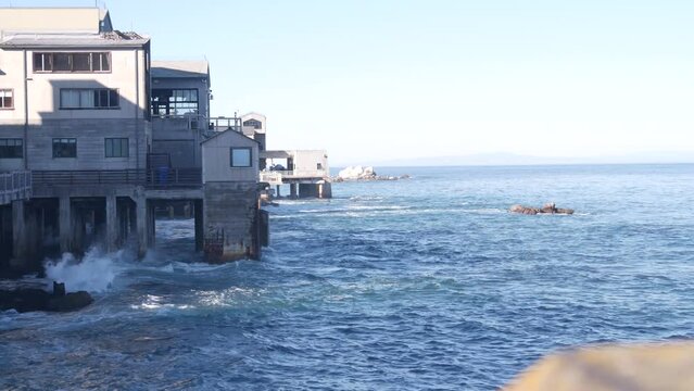 Waterfront wooden boardwalk in Monterey, California USA. Beachfront promenade on piles, pillars or pylons by ocean sea water and bay aquarium on Cannery Row street. Tourist vacations waterside resort.