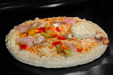 Uncooked pizza with sausage, mushroom, pepper, mozzarella on tray in electric oven. Italian cuisine, homemade bakery, fast food, semi-finished products and raw concept