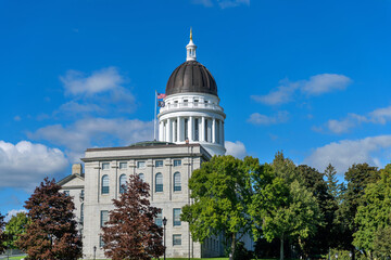 Maine State Capitol - US National Flag and the flag of National League of POW-MIA Families flying at side of the dome of Maine State Capitol building on a bright sunny Autumn day. Augusta, Maine, USA.