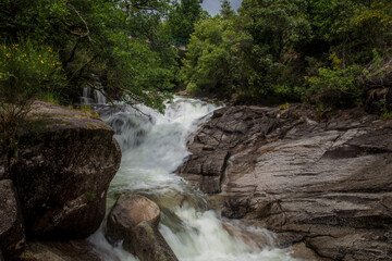 Landscape detail of waterfall of running water over large rocks.