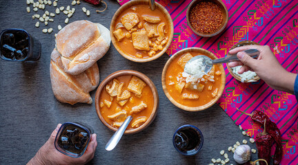 Comida mexicana, plato de menudo sobre sarape rosa.