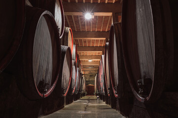 Rows of wooden wine-filled casks line the cellar of the winery, a wine vault with long tradition...