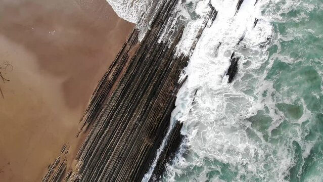 Aerial drone view of famous flysch of Zumaia, Basque Country, Spain. Flysch is a sequence of sedimentary rock layers that progress from deep-water