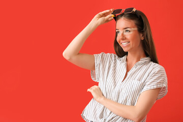 Happy young woman with sun tanned skin and sunglasses on red background