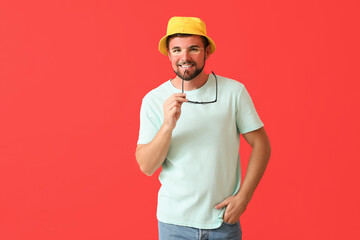 Happy young man with sun tanned skin and sunglasses on red background