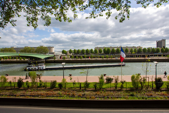 Green nature, the river Seine in May and a cargo ship maneuvering in the water