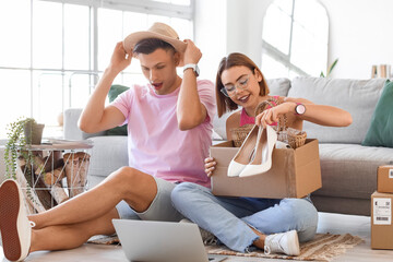 Young couple unpacking box with new clothes at home. Online shopping