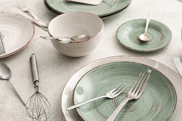 Stylish dinnerware and kitchen utensils on light table, closeup