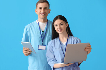 Medical assistants with laptop and tablet computer on blue background