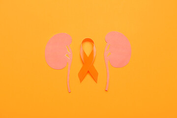 Awareness ribbon and paper kidneys on orange background