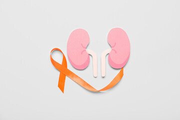 Orange awareness ribbon and paper kidneys on grey background
