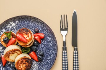 Delicious cottage cheese pancakes with berries served on beige background