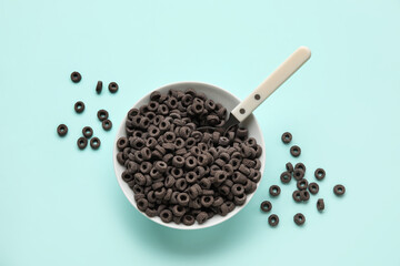 Bowl with black cereal rings on blue background