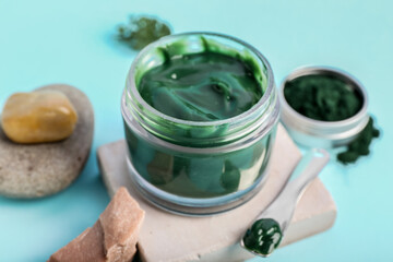 Jar of spirulina facial mask on blue background