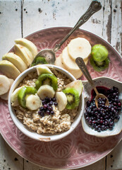 oatmeal with fruits, healthy breakfast on pink plate, blueberries,