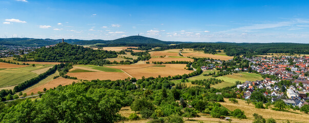 Übersicht über die mittelhessische Gemeinde Krofdorf-Gleiberg in einer Panoramaaufnahme bei sonnigem Sommerwetter mit Horizont, wolkenlosem Himmel, der Ruine der Burg Vetzberg mit ihrem Bergfried und 