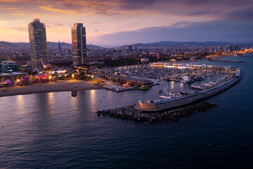 Fototapeta premium Picturesque evening aerial view of coastal area of Barcelona overlooking Olympic Harbor marina with moored pleasure yachts and modern architecture of waterfront in summer, Spain..