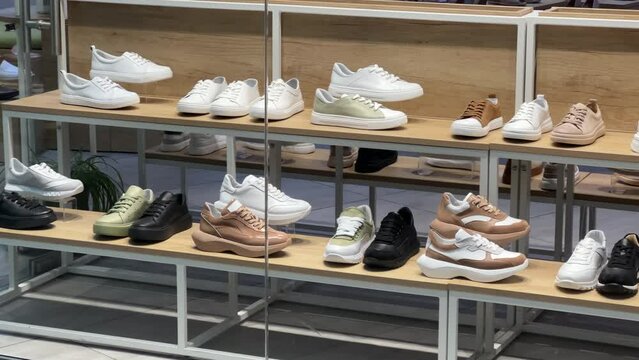 Women's casual shoes and sneakers stand on the shelves of a women's shoe store showcase