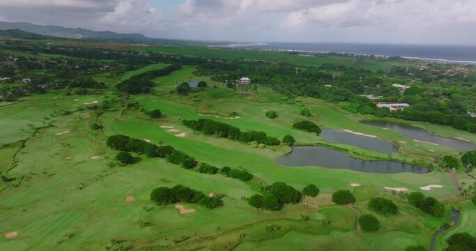 Golf hotel coast Indian ocean. Golf course and villas on the beach. Aerial view of Golf course. Establishing shot, drone flying over golf club. Summertime, sunset. The life of rich people. Mauritius