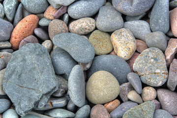Fototapeta na wymiar Beach rounded rocks in various colors from ocean