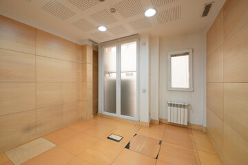 Empty room with technical floors in wood color and emergency door made of aluminum and glass