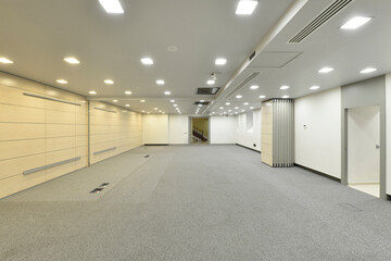 Obraz premium Large room to dedicate to empty offices, with floors covered with gray carpet and folding screens in the middle of the room
