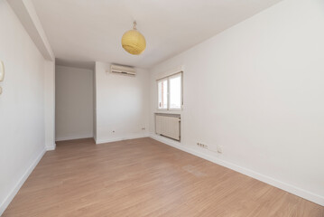 Empty room with light wood flooring, freshly painted plain white walls and a window with a radiator...