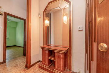 Fototapeta premium Entrance hall of a residential home with a wooden sideboard with a mirror and sconces in the foreground